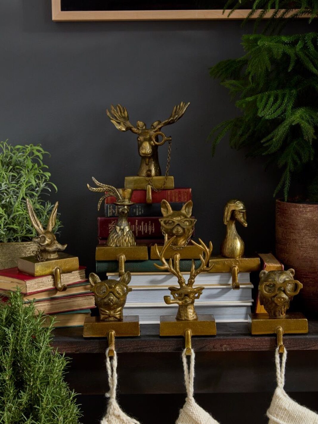 Gold animal figurines and books on a mantel with white stockings hanging below.