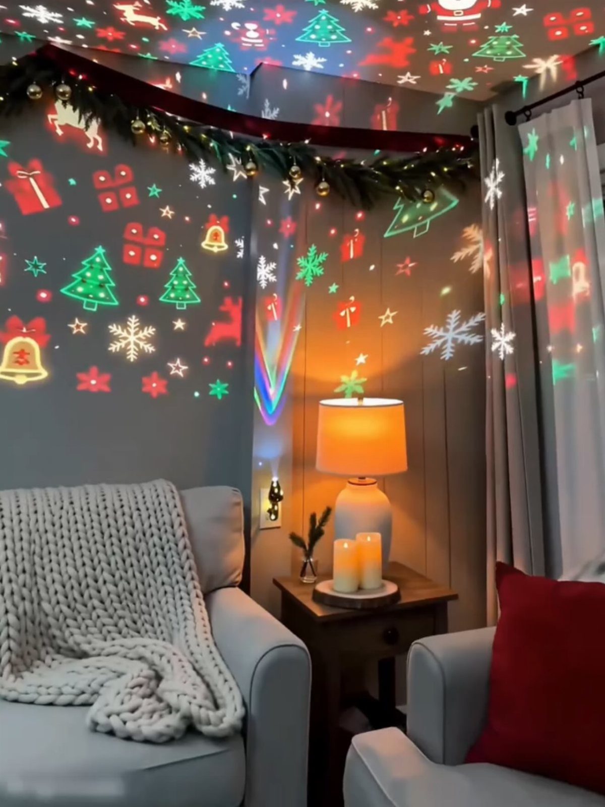 Living room with Christmas light projections of trees and snowflakes on the walls.