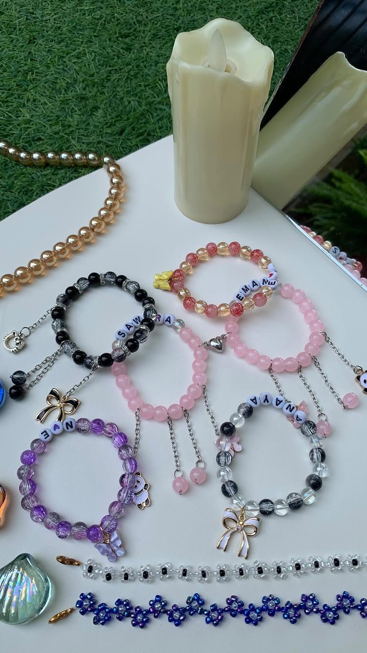 Beaded bracelets with personalized letter beads and charms on a white surface.