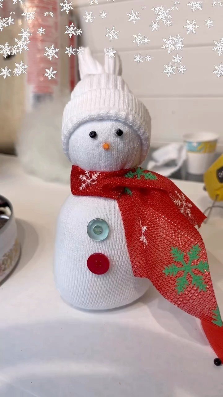 Handmade snowman sock buddy wearing a white hat and red patterned scarf.