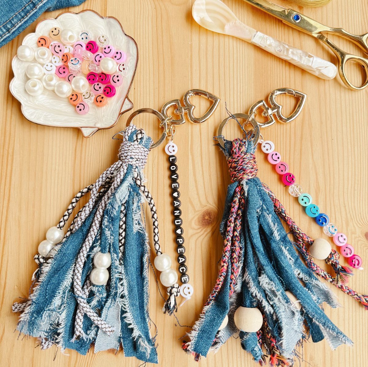 Two denim tassel keychains with colorful beads on a light wooden table.