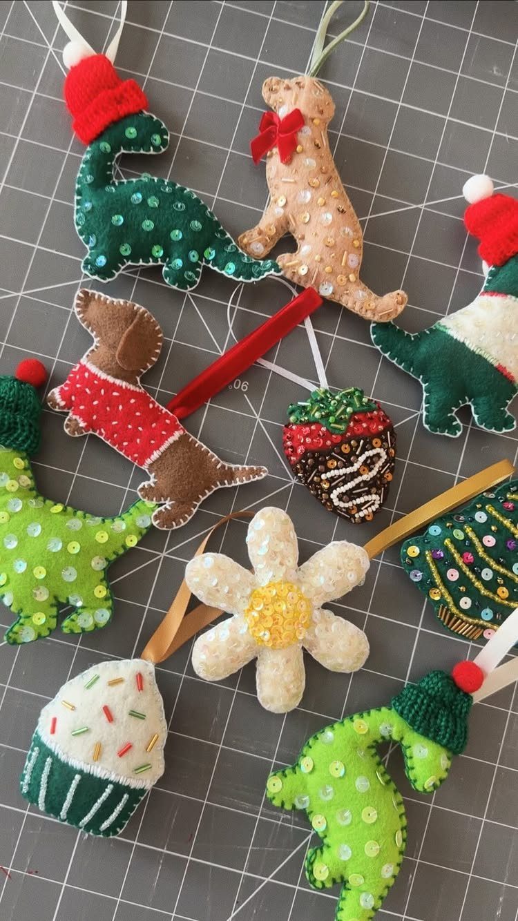 Handmade felt ornaments in various shapes and colors on a grey grid mat.
