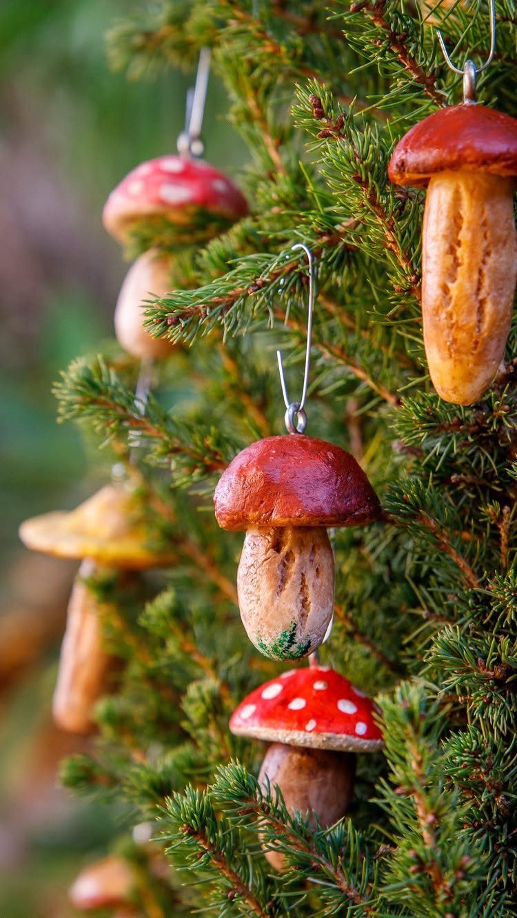 Mushroom-shaped ornaments hanging on a green pine tree branch.