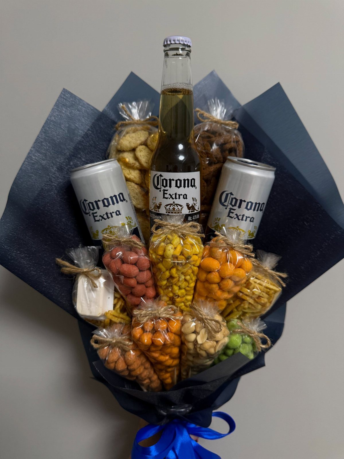 Beer and snack gift bouquet wrapped in blue paper with a blue ribbon.