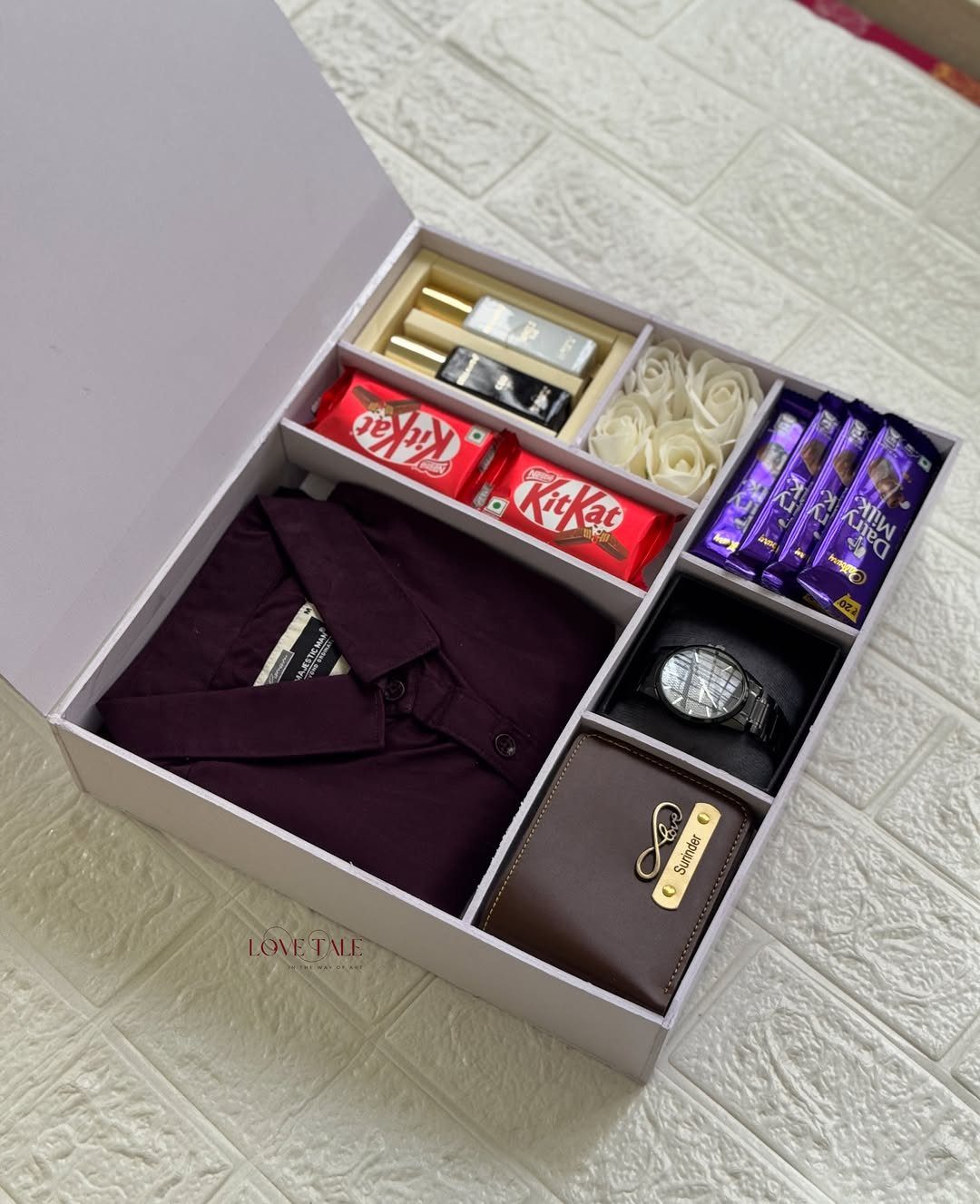 Gift box with purple shirt, brown wallet, silver watch, and assorted chocolates.
