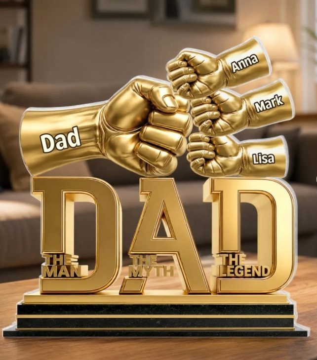 Gold Dad trophy with fist bumps and names on a wooden table