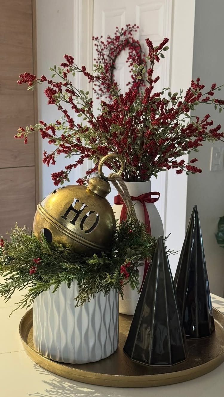 Gold HO ornament on greenery with black cone trees on a gold tray