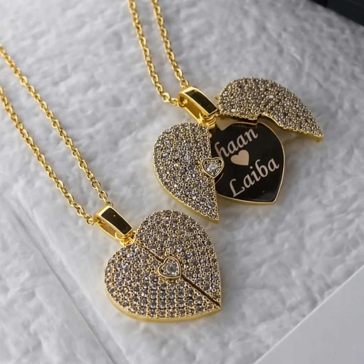 Two gold heart necklaces, one open showing engraved names Haan and Laiba.