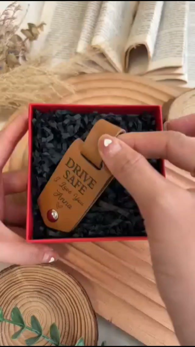 Brown leather keychain engraved with Drive Safe and a name in a red box