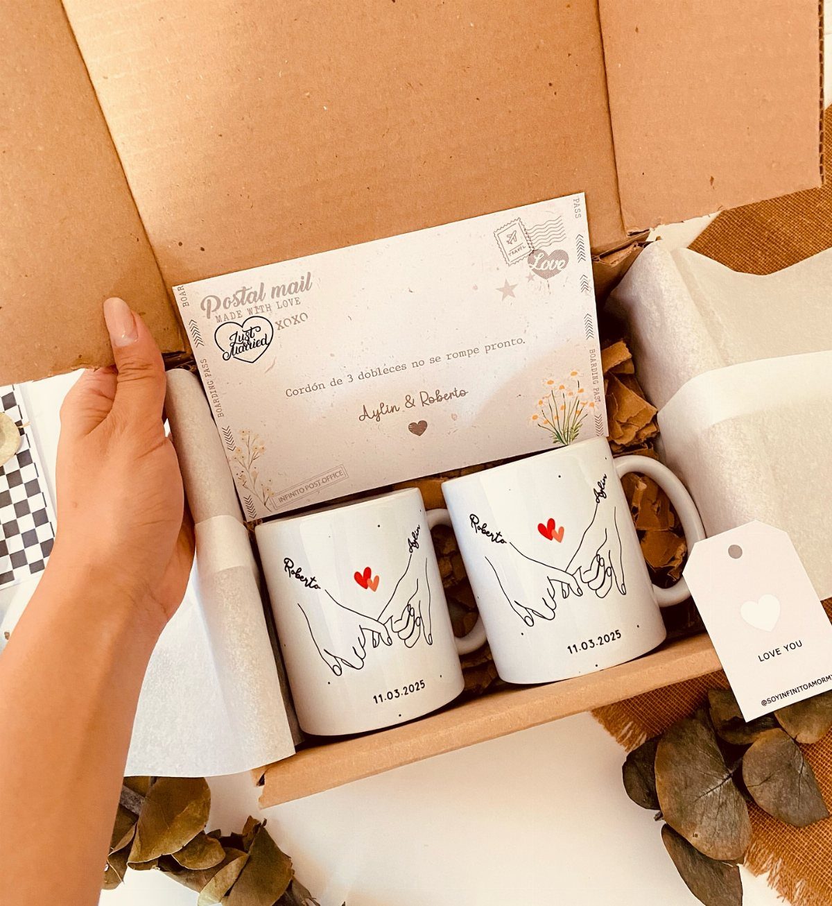 Two personalized white mugs with hand-holding illustrations inside a cardboard gift box.