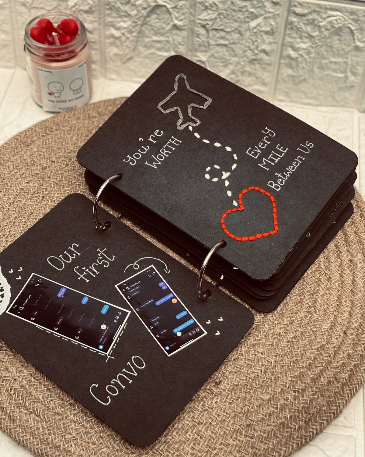 Black ring-bound photo books with romantic messages and chat screenshots on a mat.