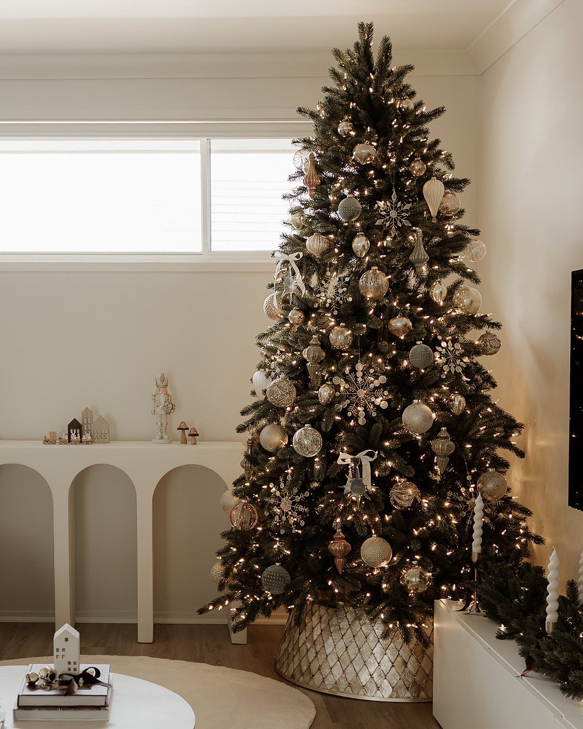 Decorated Christmas tree with gold and silver ornaments and warm white lights.
