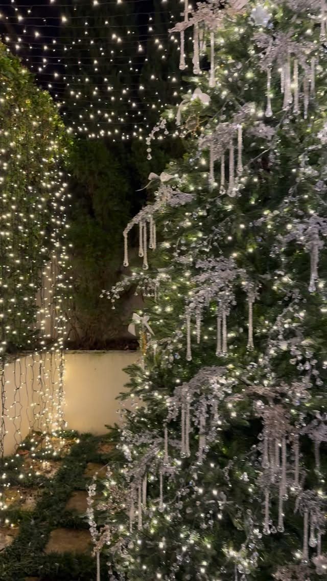 Decorated Christmas tree with silver icicles and white lights in a night garden