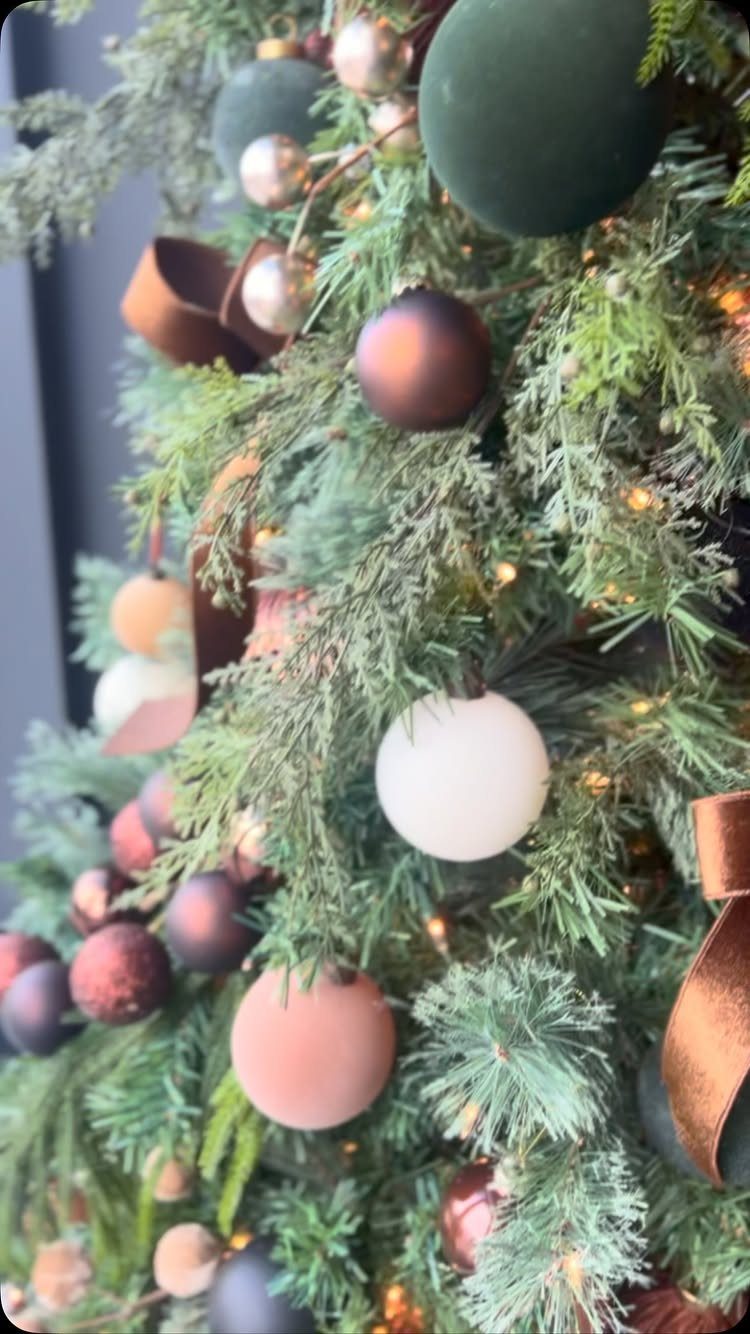 Green Christmas tree decorated with matte and metallic brown, white, and green ornaments.