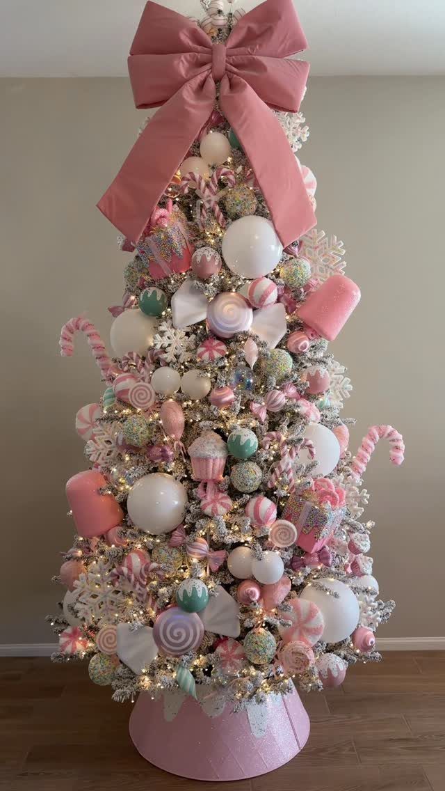 Christmas tree decorated with pink, mint, and white candy-shaped ornaments and a large bow.