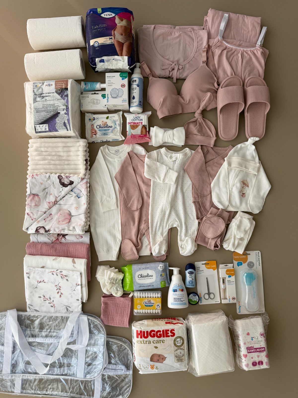 Maternity and baby essentials including pink clothing, diapers, and toiletries for hospital bag.