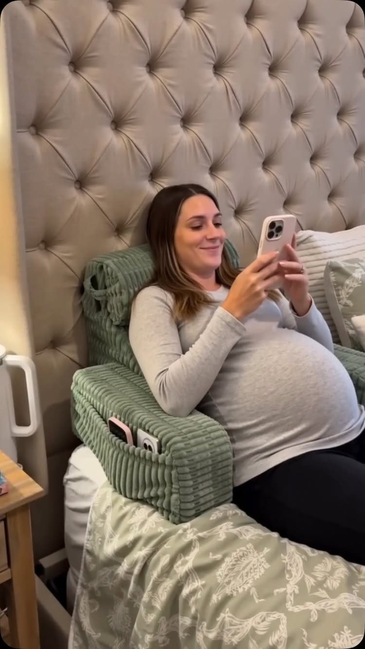 Pregnant woman resting in bed using a green corduroy pregnancy support pillow