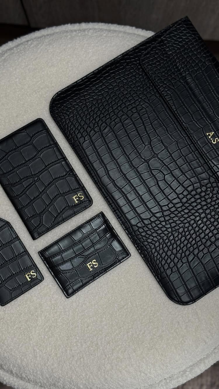 Black crocodile-embossed leather portfolio and wallets with gold initials on white fabric