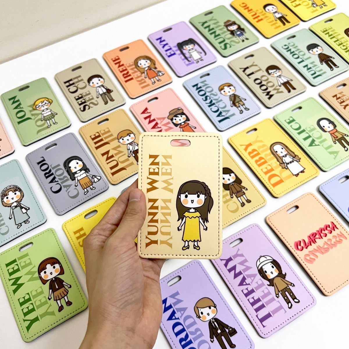Personalized leather ID badge holders with cartoon characters and names on a white table