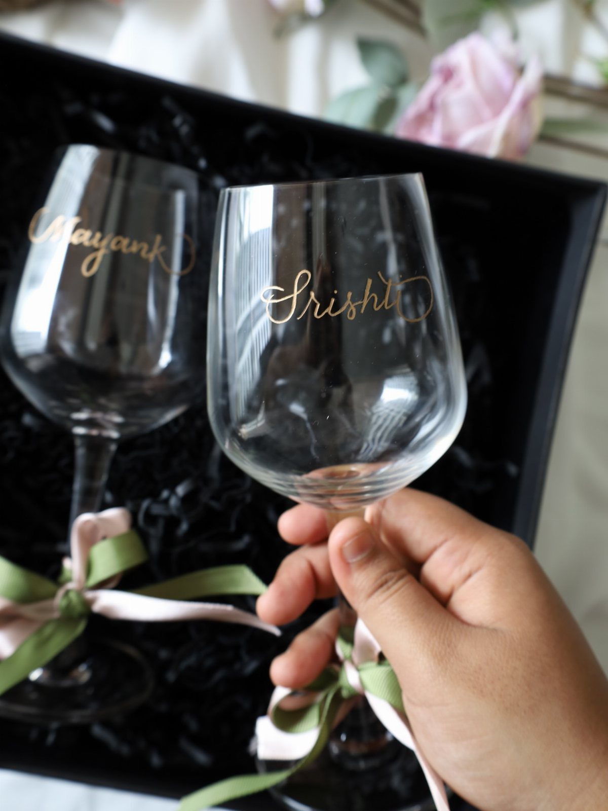Personalized wine glasses with gold names and ribbons in a black gift box