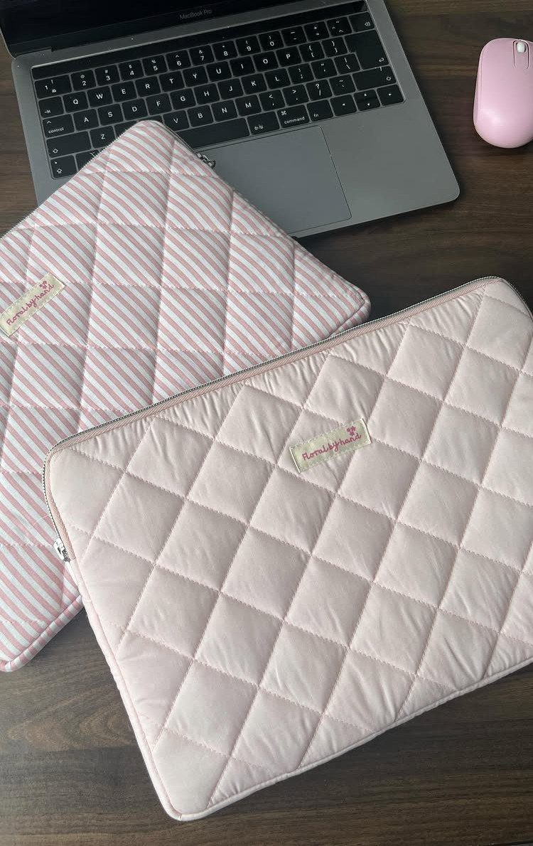 Two quilted laptop sleeves in pink and striped patterns on a wooden desk.