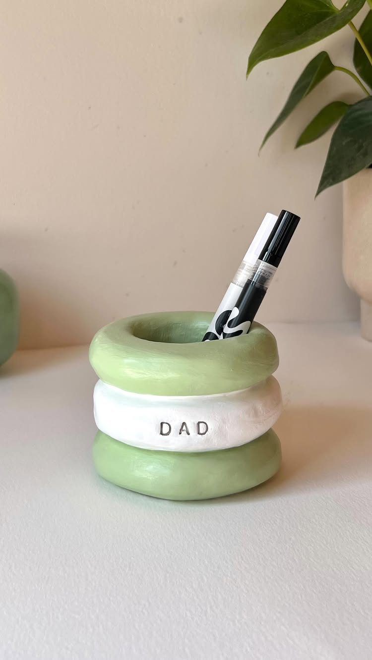 Ceramic pen holder with green and white rings labeled DAD holding a marker.