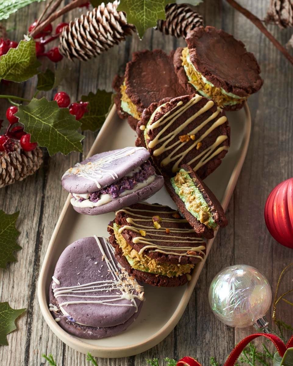 Assorted chocolate and purple whoopie pies on a platter with Christmas decorations.