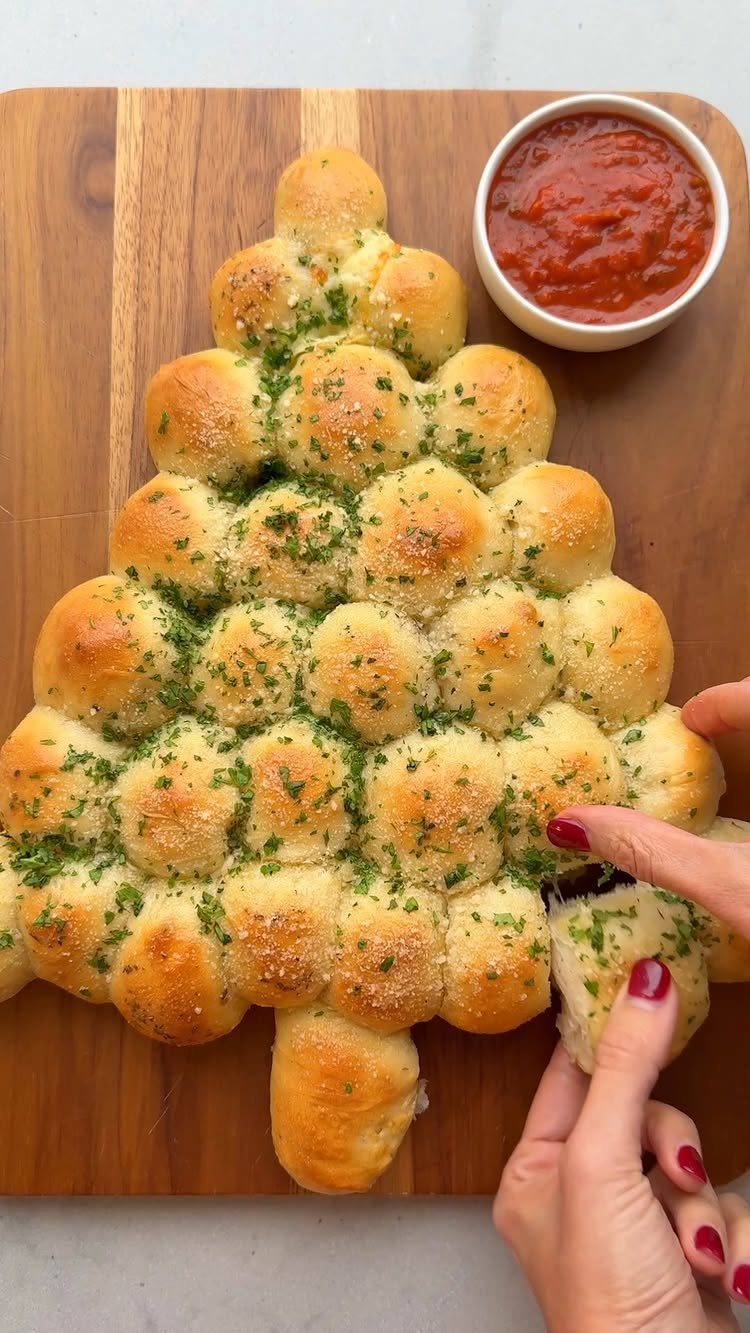 Christmas tree shaped pull apart bread with parsley and a side of marinara sauce