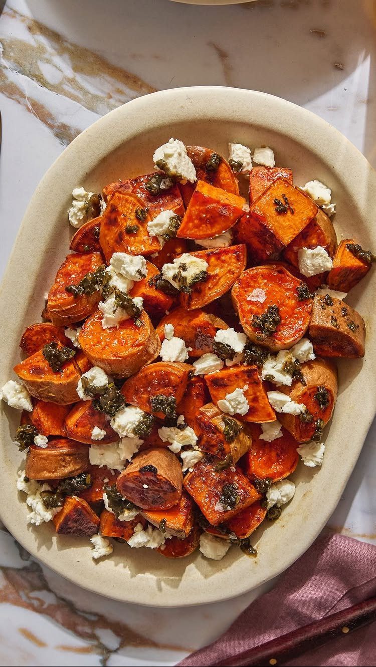 Roasted sweet potato chunks with feta cheese and pesto in a cream bowl