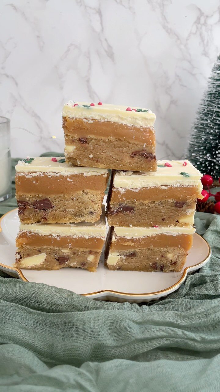 Layered millionaire's bars with caramel and white chocolate on a white plate.