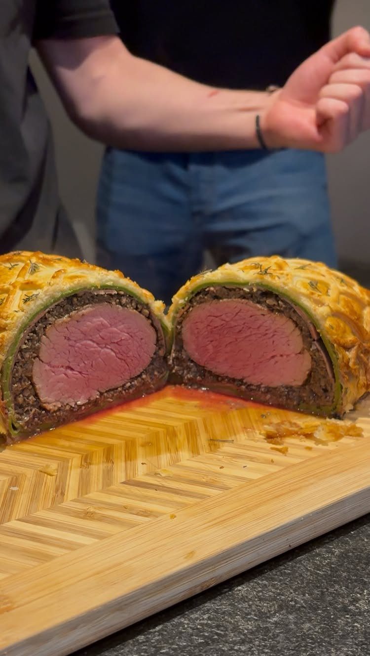 Sliced stuffed beef tenderloin with pastry crust on a wooden cutting board