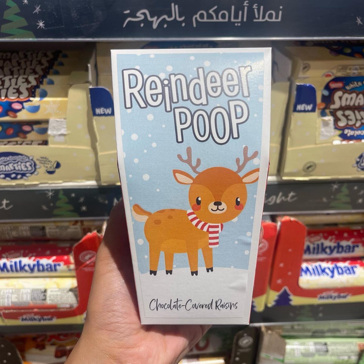 Reindeer Poop chocolate-covered raisins box held in a hand in a candy store.