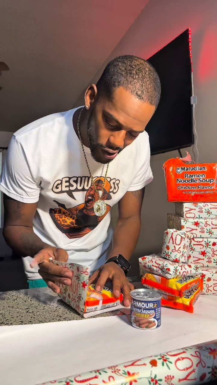 Man wrapping instant ramen noodles in festive Christmas paper as a funny gift.