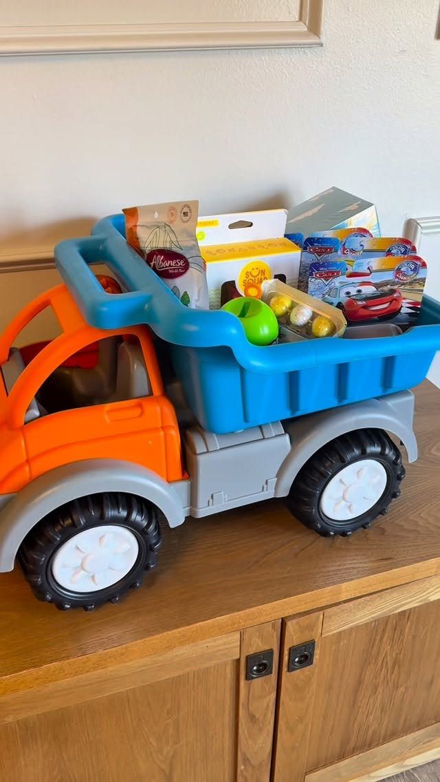 Toy dump truck filled with Easter treats and eggs on a wooden cabinet