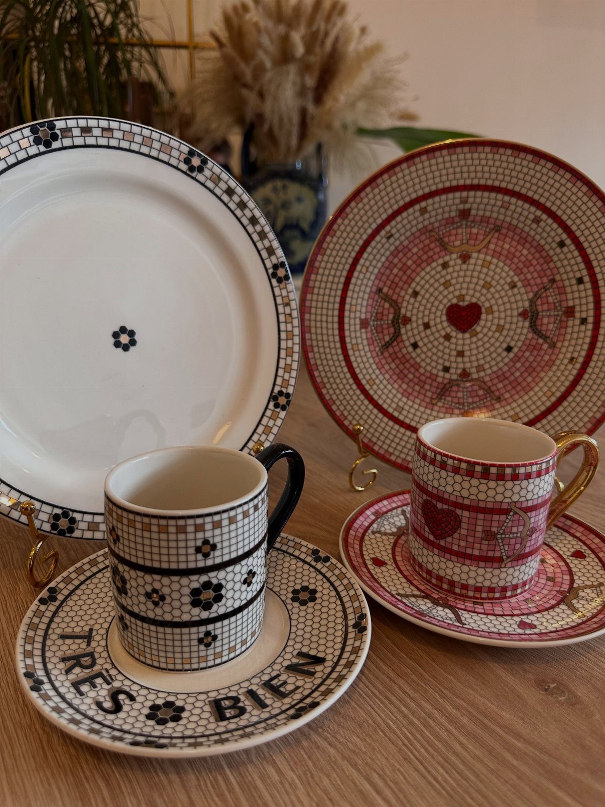 Mosaic patterned ceramic plates and mugs with red and black details on wood.