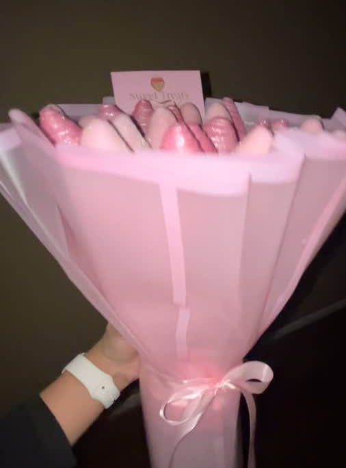 Bouquet of pink chocolate-covered strawberries wrapped in pink paper with a ribbon.