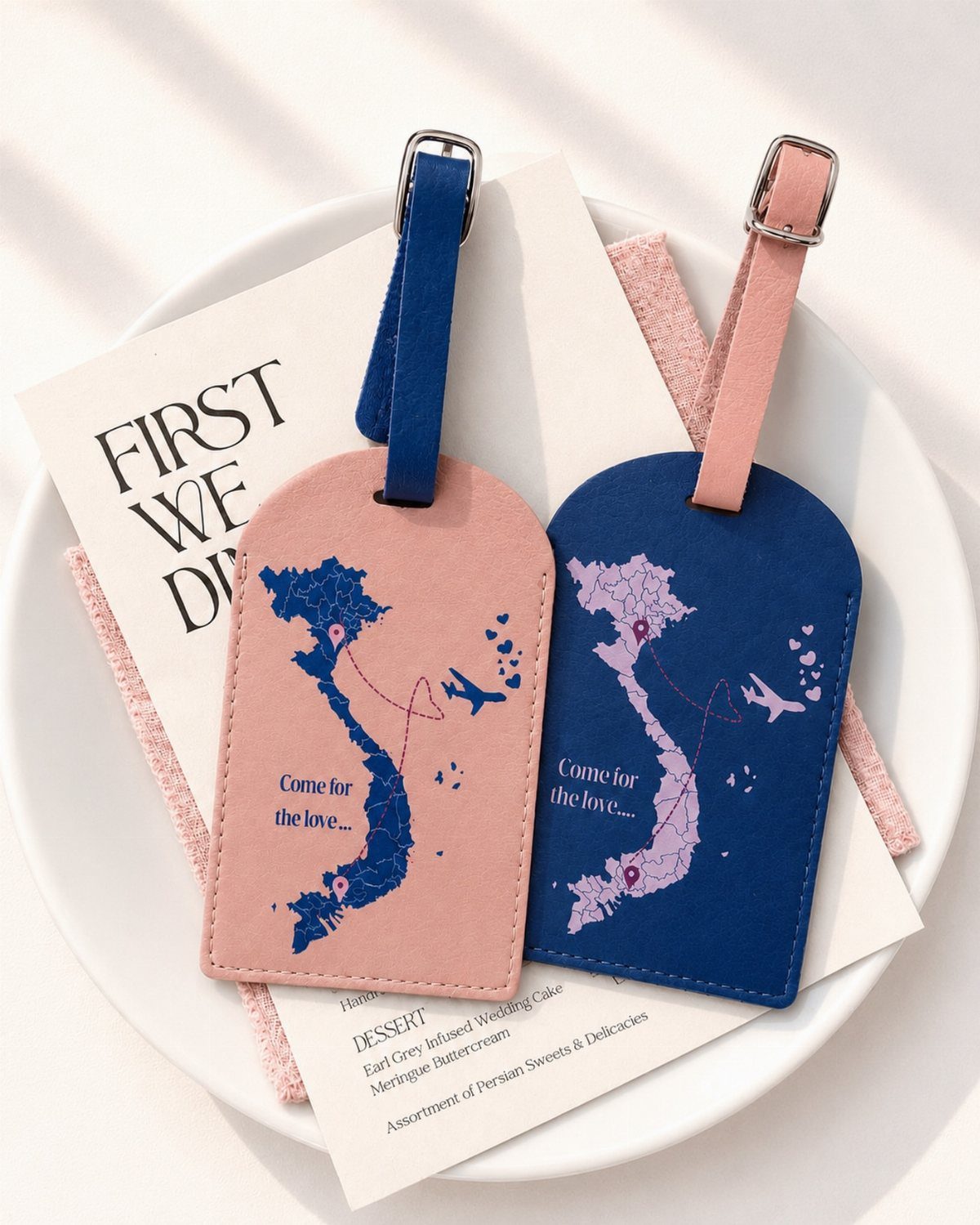 Two leather luggage tags in pink and blue featuring a map of Vietnam.