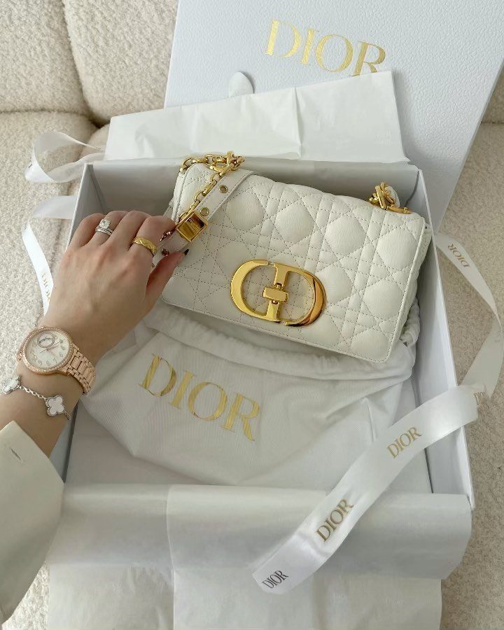 White quilted Dior handbag with gold logo inside a branded white gift box.