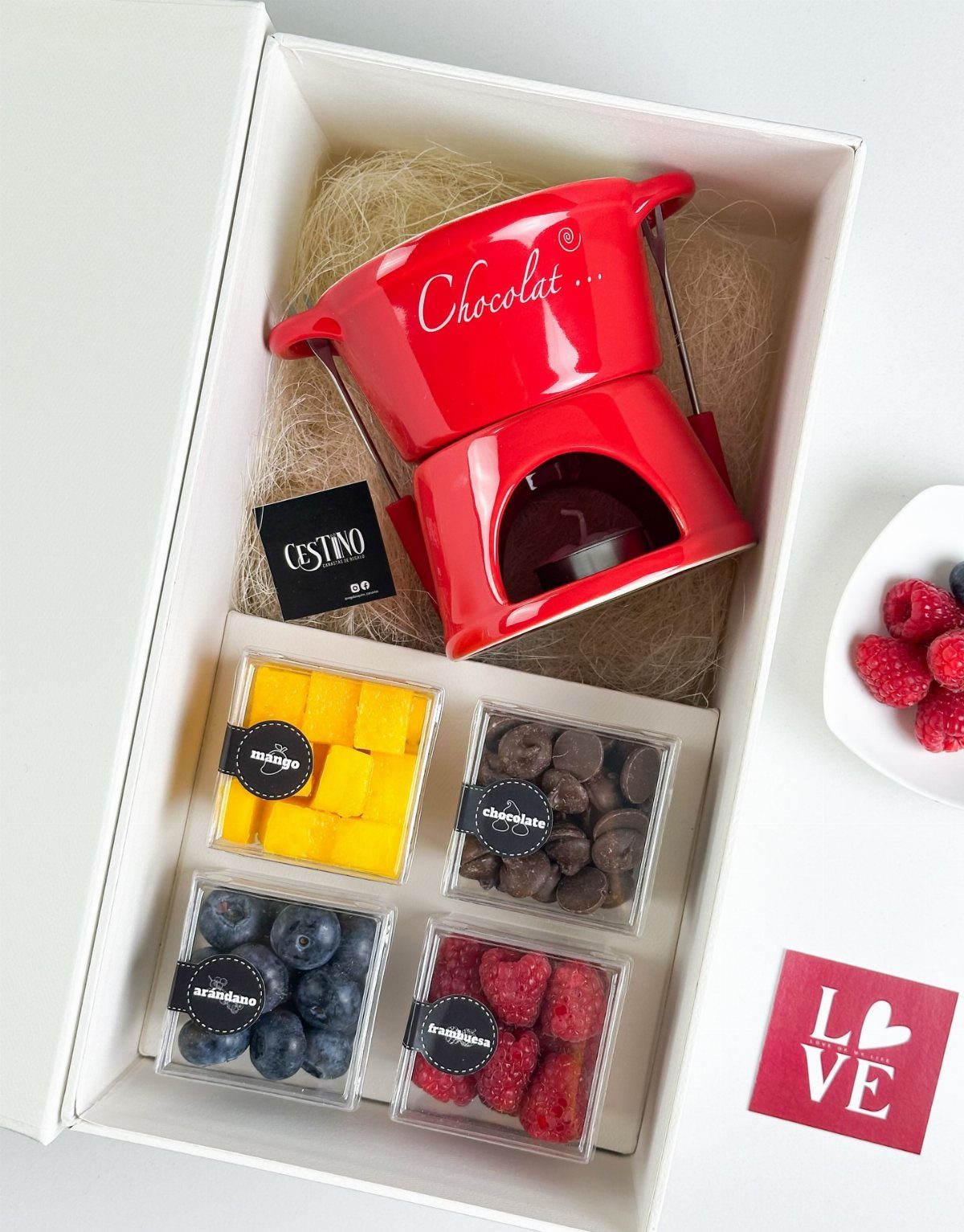 Red chocolate fondue pot set in a gift box with fresh fruit containers.