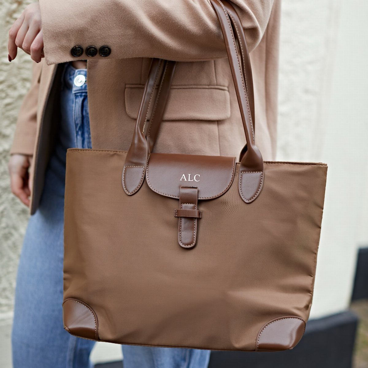 Brown personalized tote bag with gold initials held by a person in blazer