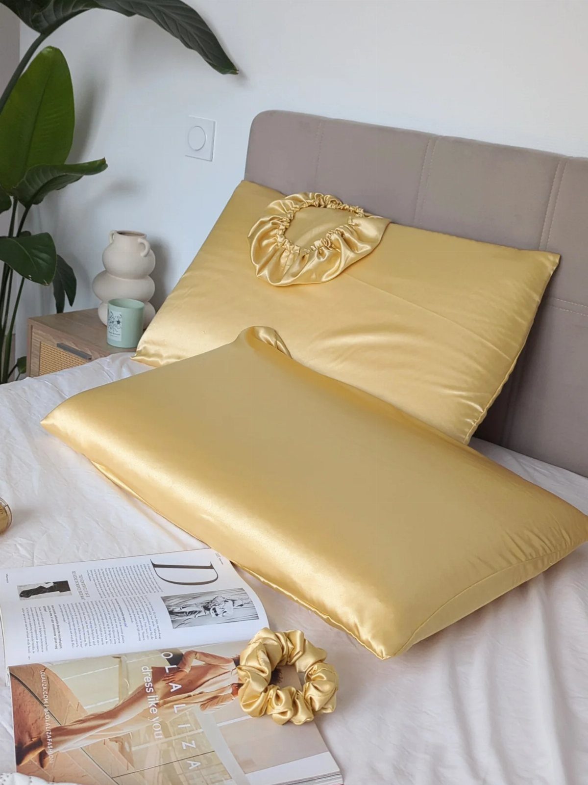 Gold satin pillowcases and matching scrunchies on a white bed with a magazine.