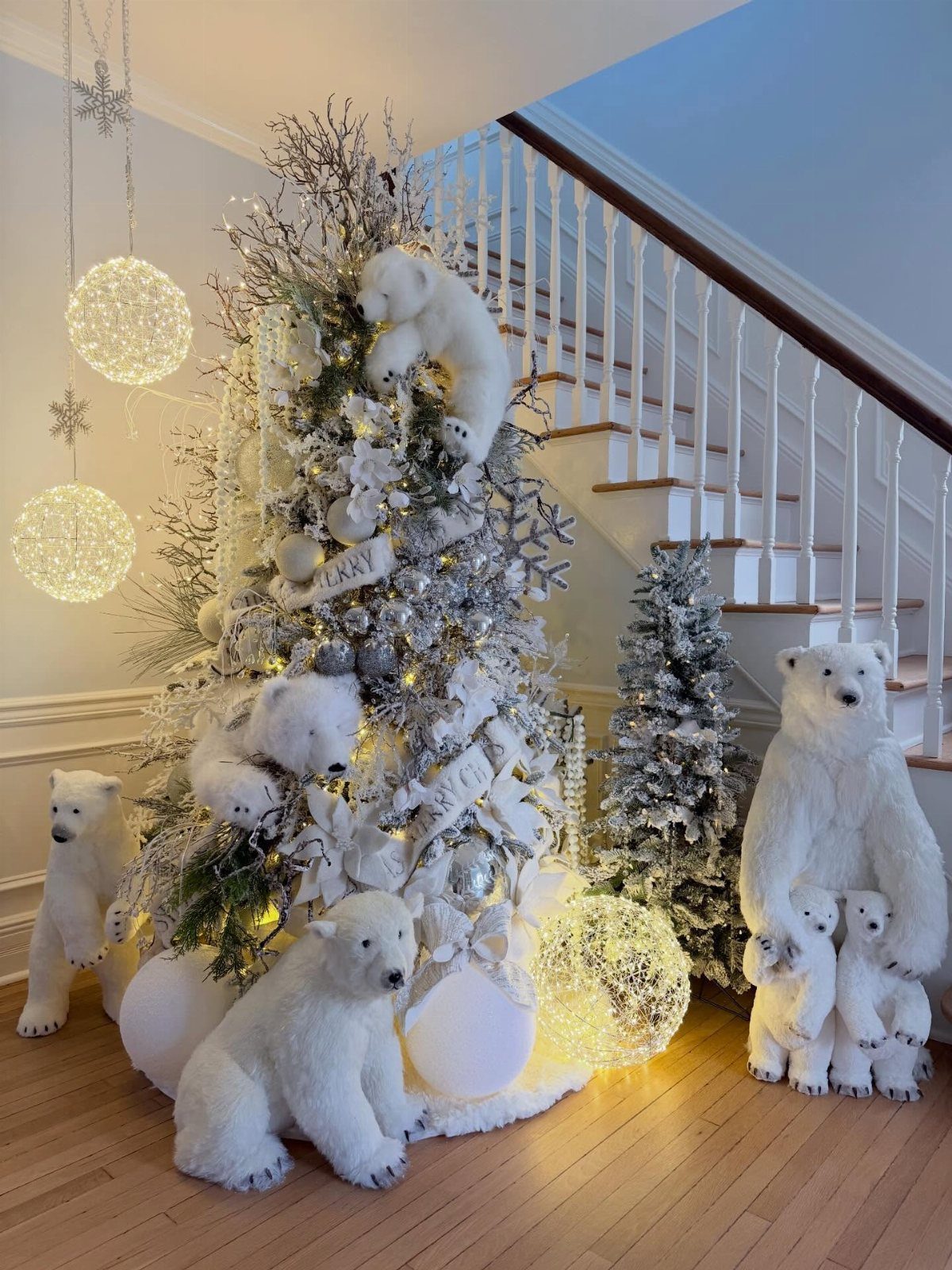 Flocked white Christmas tree decorated with silver ornaments and white polar bear plushies.