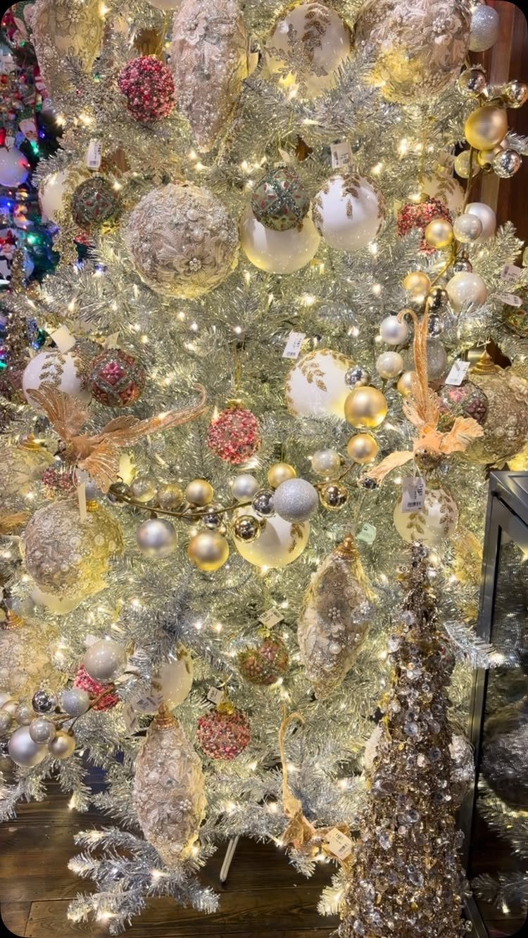 Silver tinsel Christmas tree decorated with gold and red ornaments and warm lights.