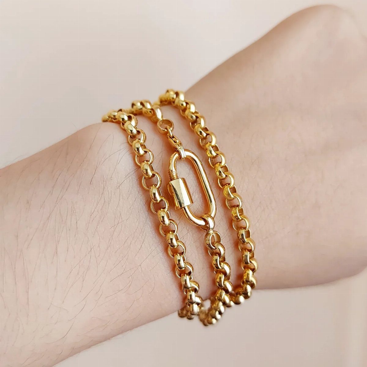 Gold chain bracelet with a large clasp worn on a person's wrist.