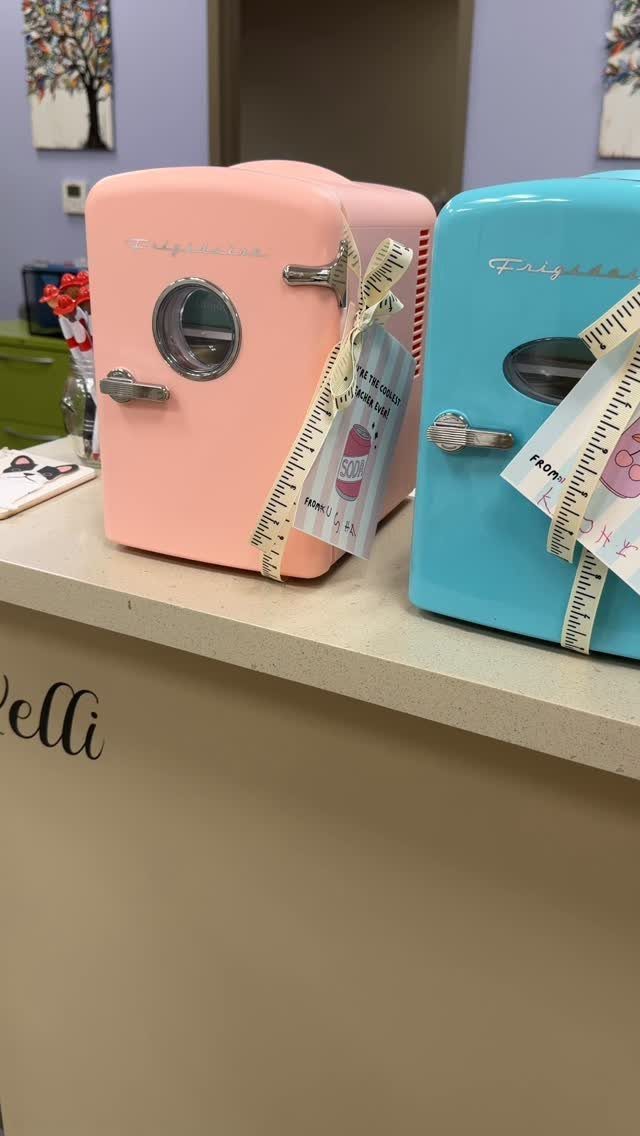 Two retro mini fridges in pink and blue sitting on a beige counter.