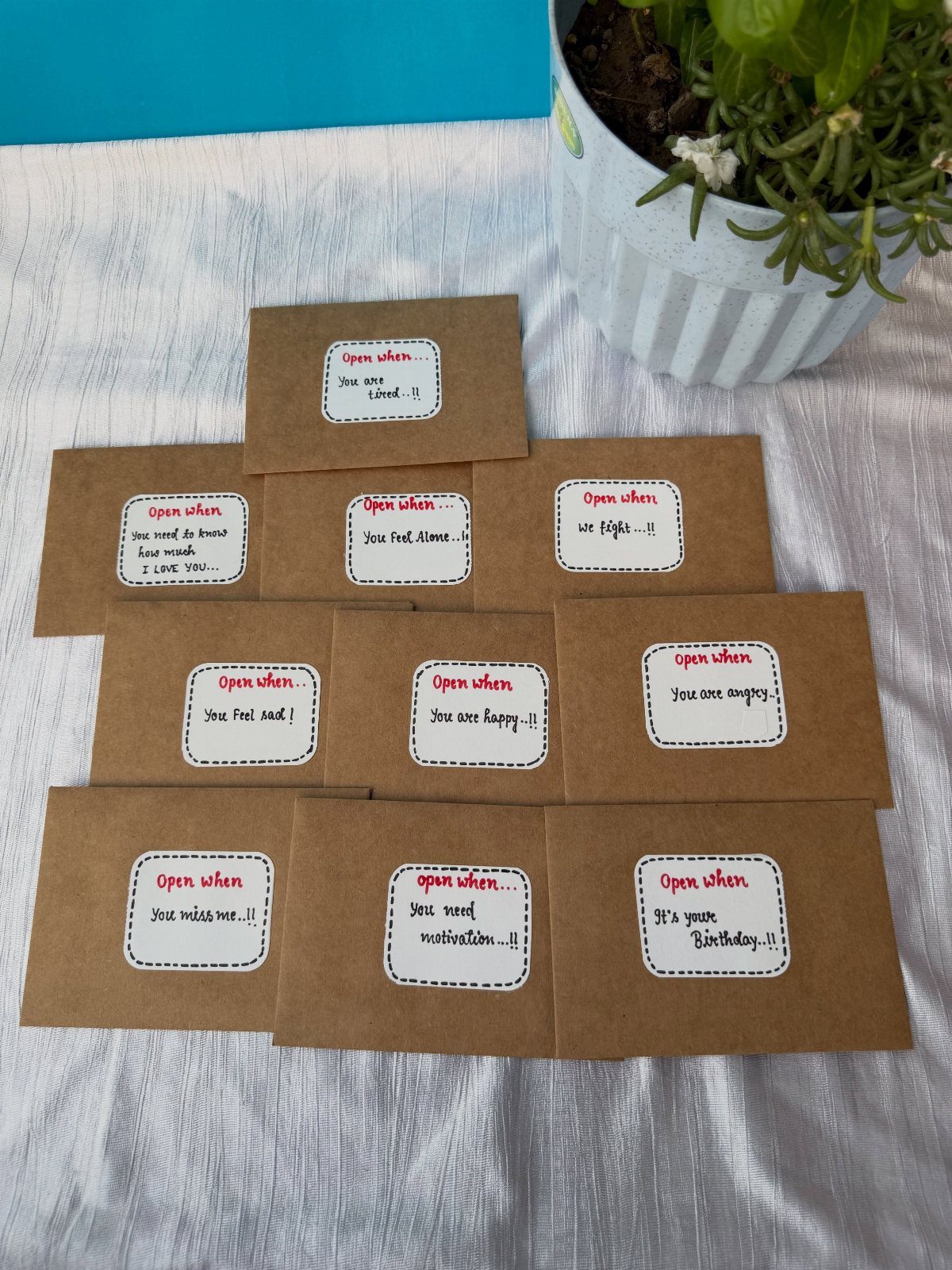 Brown kraft envelopes with handwritten Open when labels arranged on a white cloth.