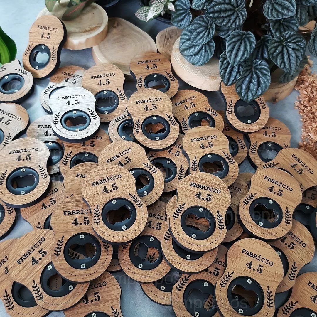 Wooden bottle openers engraved with a name and number scattered near a plant.