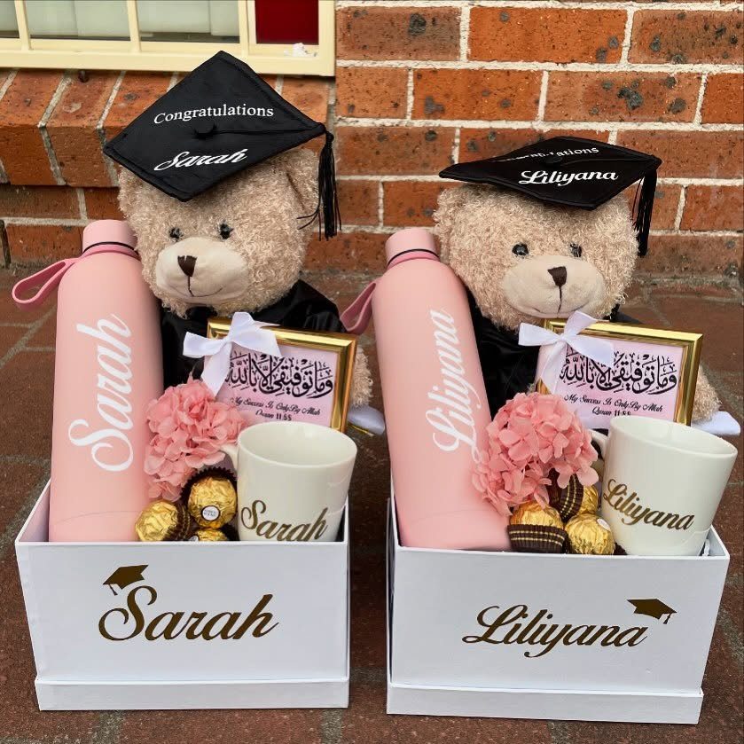 Two personalized graduation gift boxes with teddy bears, pink bottles, and white mugs.