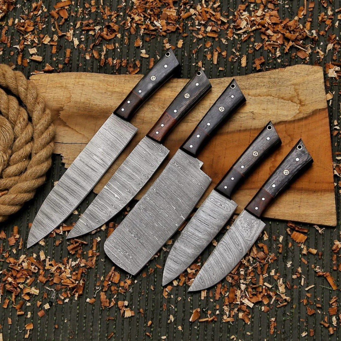 Damascus steel kitchen knife set with wooden handles on a rustic wooden board