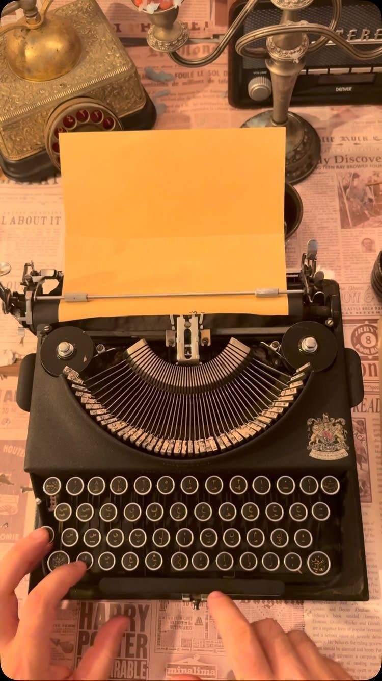 Black vintage typewriter with yellow paper on a desk with antique accessories